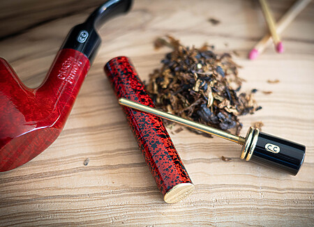 Bourre-pipe CHACOM en bruyère avec cure-pipe intégré. Finition vernie rouge et noir, agrémentée d'une double bague.