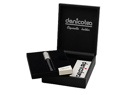 Soigneusement présenté dans un joli coffret noir, le fume cigarette DENICOTEA est accompagné d’un embout acrylique de 73mm et d’un second de 50mm, le coffret inclut également une pochette de 10 filtres 9mm DENICOTEA. Le fume cigarette est orné de cristaux SWAROVSKI Cristal et il est doté d'un système d'éjection de la cigarette.