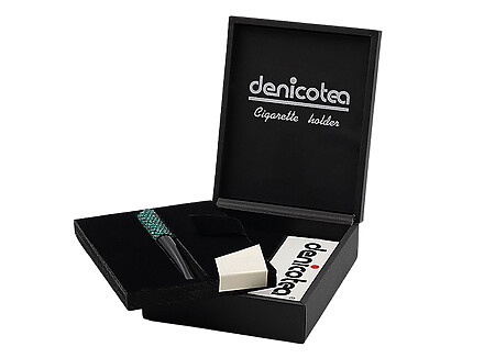 Soigneusement présenté dans un joli coffret noir, le fume cigarette DENICOTEA est accompagné d’un embout acrylique de 73mm et d’un second de 50mm, le coffret inclut également une pochette de 10 filtres 9mm DENICOTEA. Le fume cigarette est orné de cristaux SWAROVSKI Vert et il est doté d'un système d'éjection de la cigarette.