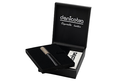 Soigneusement présenté dans un joli coffret noir, le fume cigarette DENICOTEA est accompagné d’un embout acrylique de 73mm et d’un second de 50mm, le coffret inclut également une pochette de 10 filtres 9mm DENICOTEA. Le fume cigarette est orné de cristaux SWAROVSKI Or et il est doté d'un système d'éjection de la cigarette.